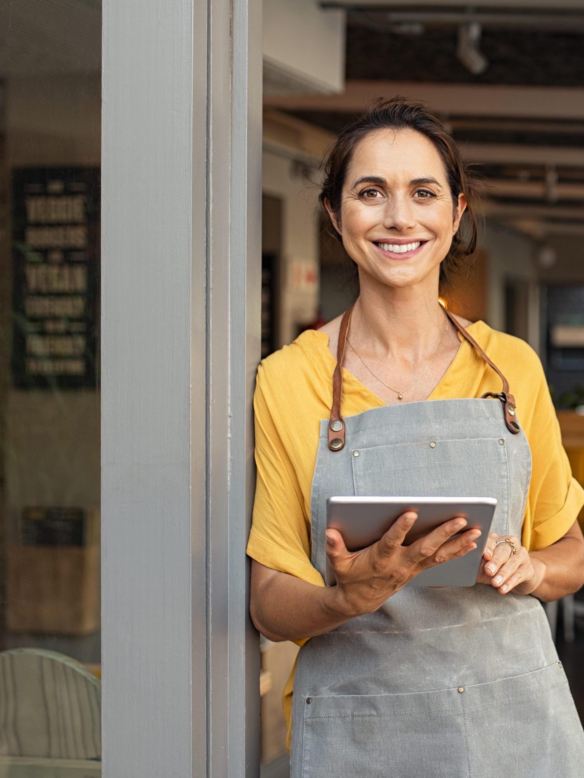 Portrait of happy woman standing at doorway of her store.